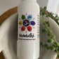 A spray bottle labeled 'Samadhi - Chakra Balancing Mist' with a white label in a bowl shaped like receiving hands and a plant.