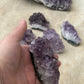 Amethyst crystal cluster being held by a hand in front of the camera as a close up view.