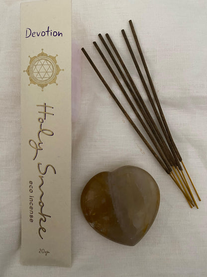 Devotion Incense Packaged next to loose incense sticks and a golden healer crystal heart.