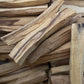 A pile of dry, irregularly shaped Palo Santo sticks with a natural, earthy scent.