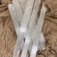 Multiple Raw Selenite Sticks placed on a textured fabric surface.