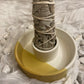 A bundle of Californian White Sage standing in a smudge stick holder on white fabric with scattered howlite stones.