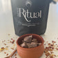 Small terracotta bowl of cacao pieces with a 300g black bag labeled 'Sacred Ritual' in the background.