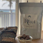 1kg bag of Sacred Ritual Cacao with a bowl of Cacao pieces on a wooden table.