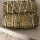 Multiple bundles of Eucalyptus leaves tied with twine on a white textured surface.