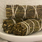 Multiple mugwort bundles tied with twine laying flat on a textured surface. 