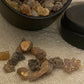 Close up of Myrrh, a  brown resinous substance on a textured beige surface