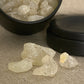A small black tin on White Copal showing a close up image of white copal pieces spilling out in front.