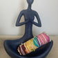 Colourful rose petals tied to Californian White sage bundle to represent each colour of the chakras cradled in the lap of a feminine meditating statue.