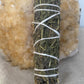 Woven mugwort bundle tied with twine standing in front of a citrine crystal slab on beige fabric.