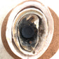 Close-up of a charcoal disc cradled on top of three abalone shells of different sizes sitting on a cork disc. Decorative.