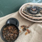 Myrrh resin in a small black tin on a textured beige surface.