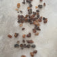 Loose myrrh, with earthy tones of black, brown and amber that are scattered on a textured surface as a close up shot.