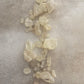 Collection of white copal resin scattered on a light coloured texture surface showing its crisp purity in colour featuring cream, pink and grey tones.