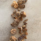 Close up photo of raw pieces of Dark Copal resin scattered on a light textured surface.